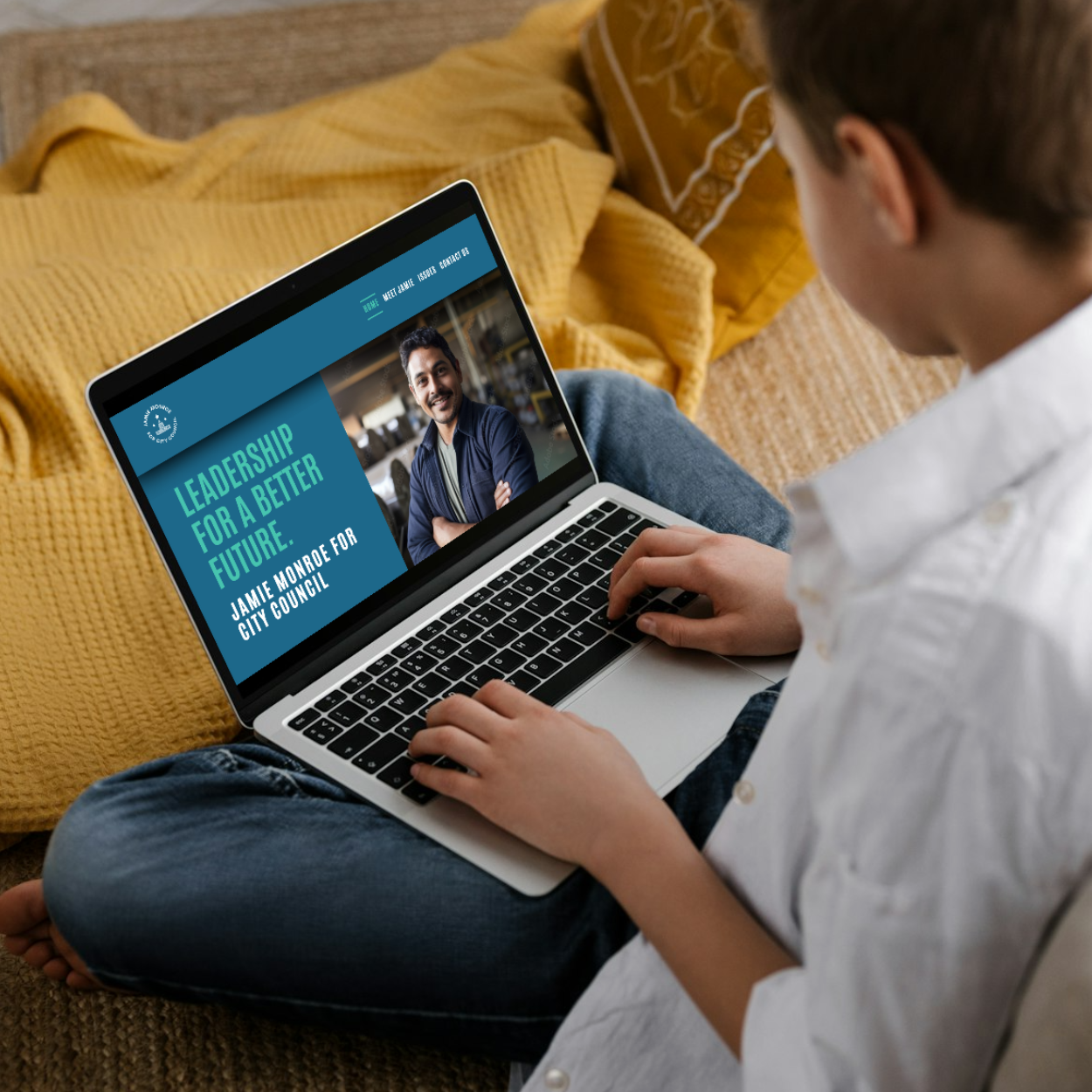 A boy is sitting on the floor using a laptop that says leadership for a better future