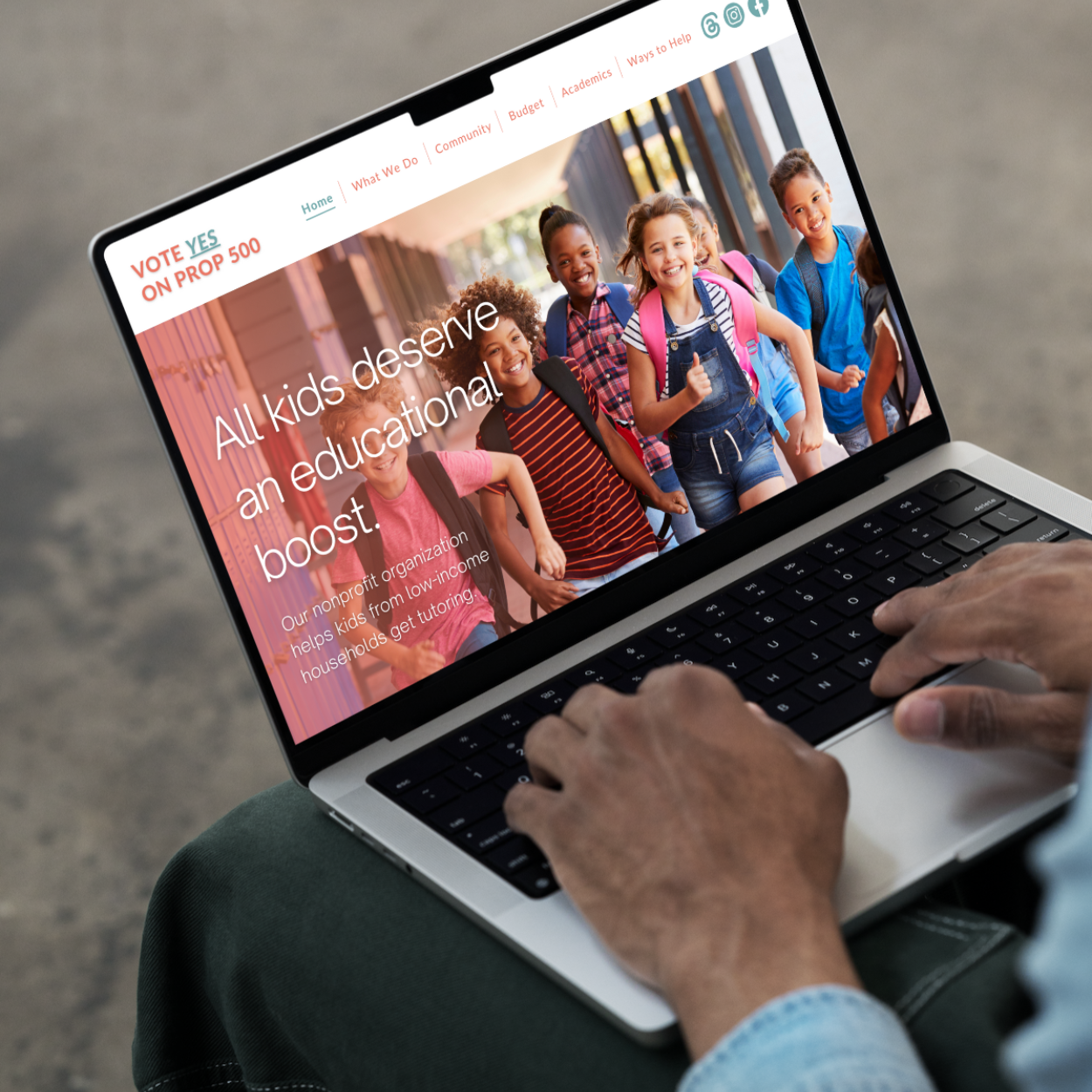 A person is typing on a laptop with a picture of children on the screen.