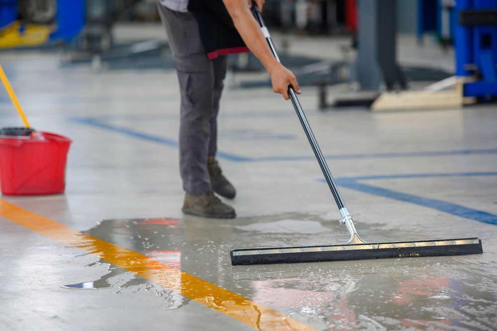 a person is cleaning the floor of a garage with a mop .