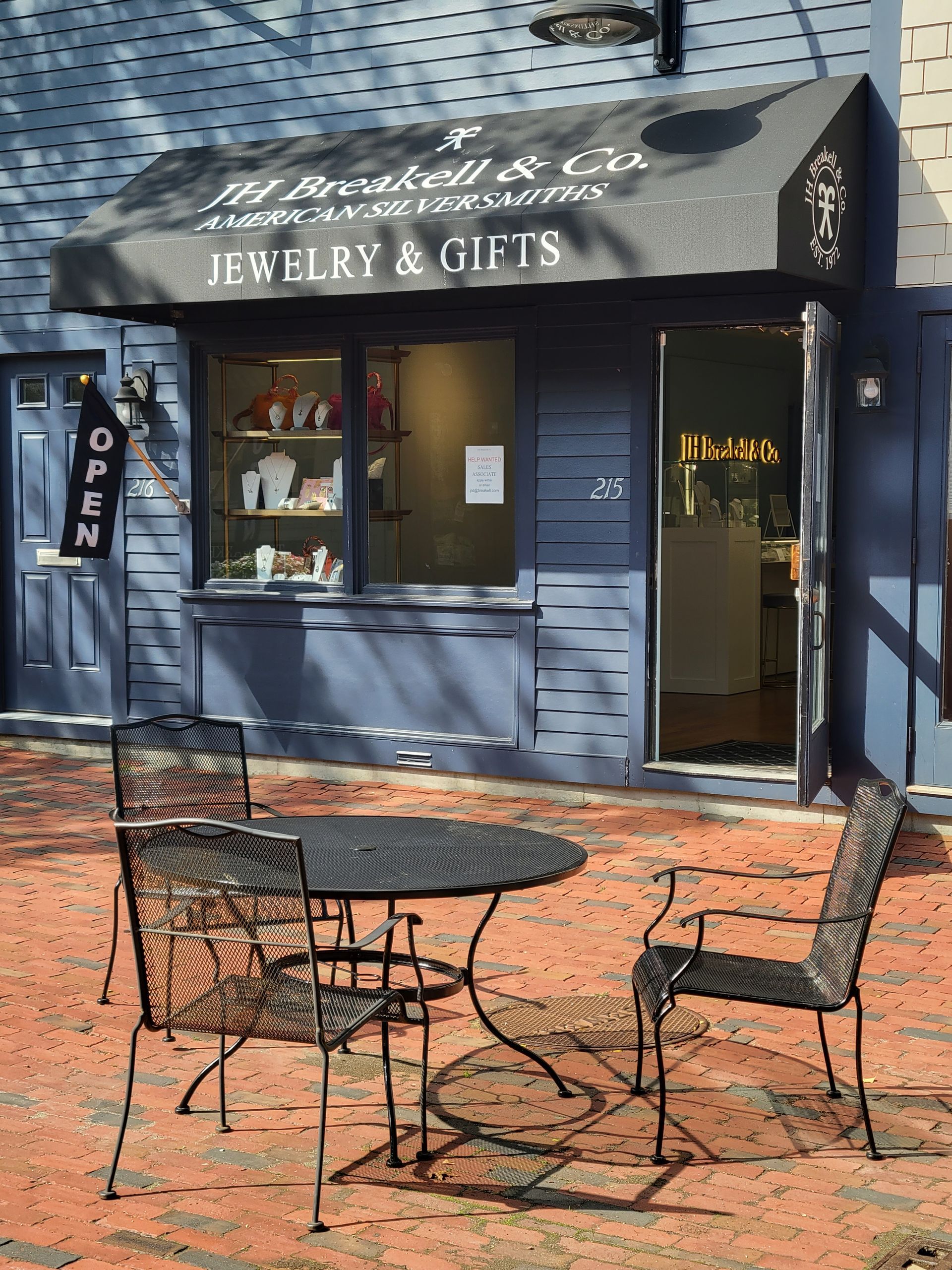 A jewelry and gifts store with a table and chairs outside