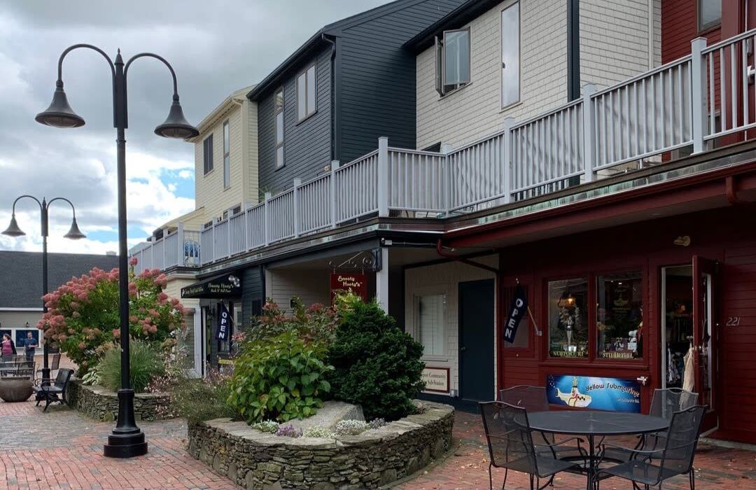 A row of buildings with tables and chairs in front of them.