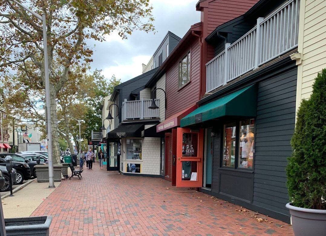 A row of shops on a brick sidewalk in a small town.