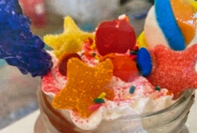 A close up of a milkshake with candy and sprinkles