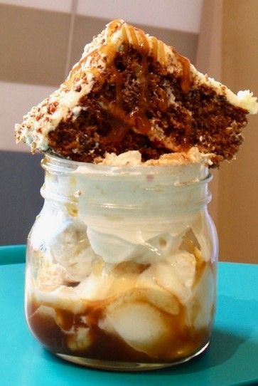 A jar filled with ice cream and a piece of cake on top.