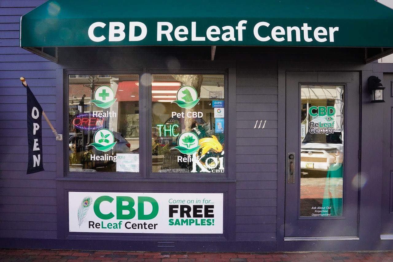 The front of a cbd releaf center with a green awning.