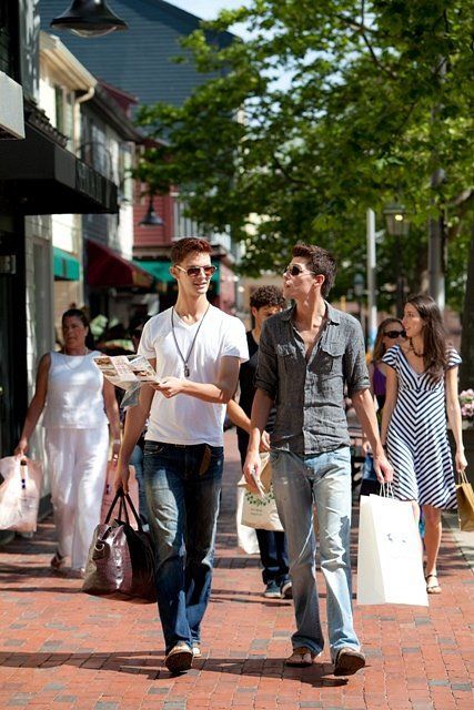 A group of people are walking down a brick sidewalk.