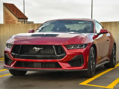 A red ford mustang is parked in a parking lot.