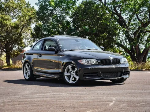 A black bmw 1 series coupe is parked in a parking lot.