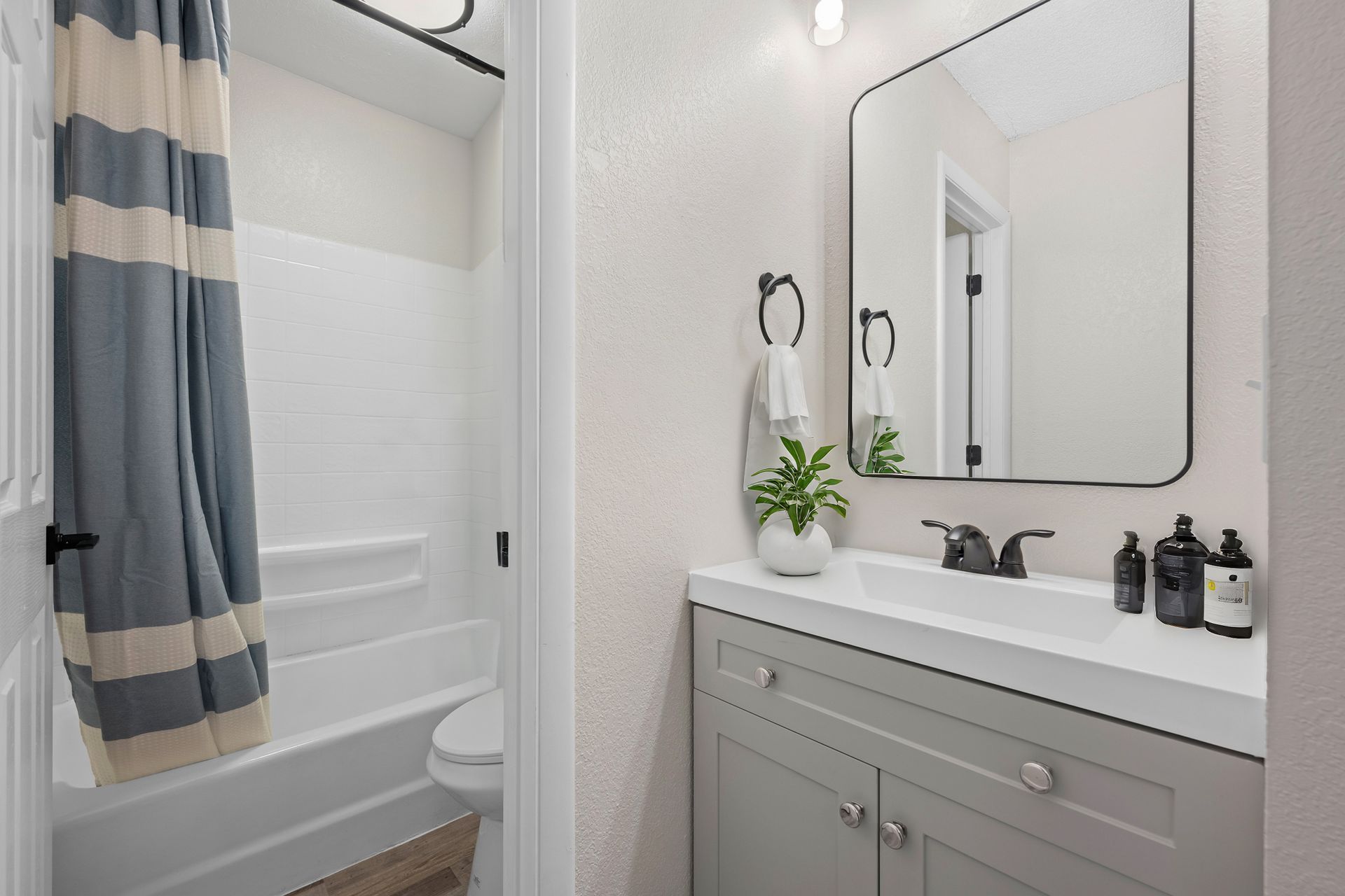 Photo of a bathroom with a door separating the sink area from the toilet and tub area