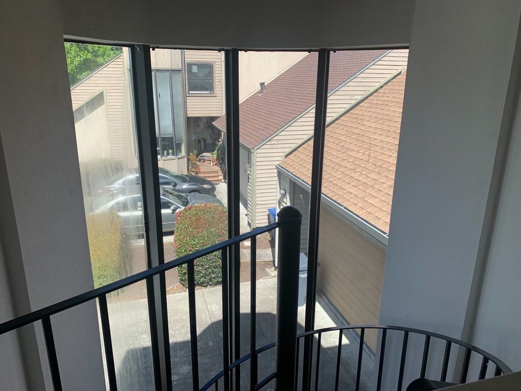 A view from a high vantage point looking down through large windows at a driveway, parked cars, and neighboring houses.