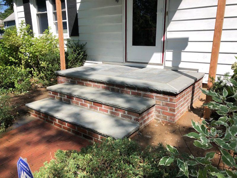red brick stoop with light grey stone steps leading front entrance of a house
