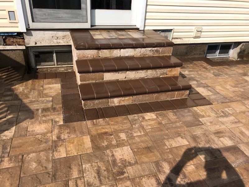 multi step stoop made of dark brown stone leading to a stone patio