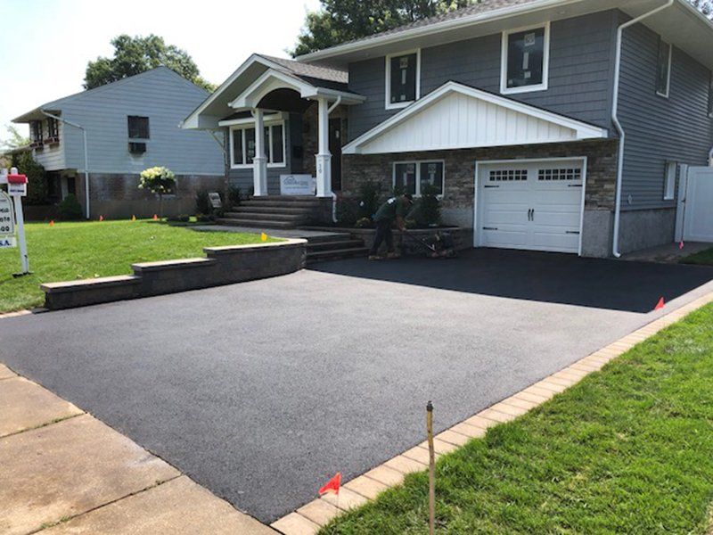 front of house with asphalt driveway with red bricks around it