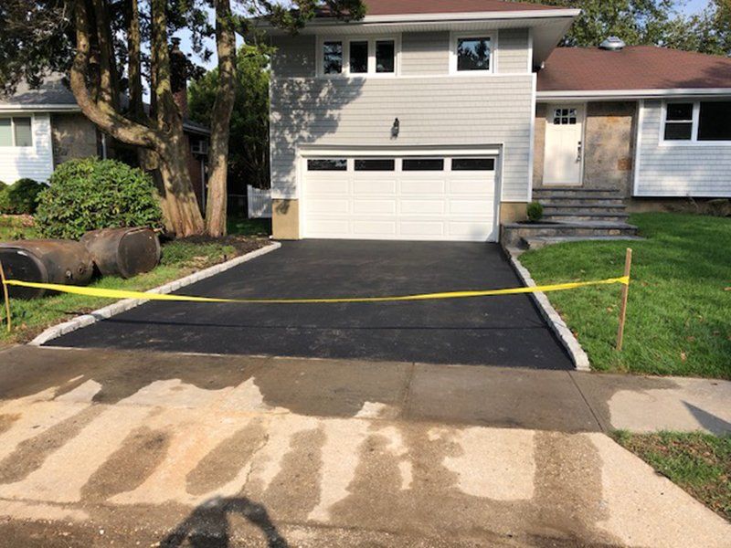 house with a white garage that has caution tape at the driveway entrance , the stonework needs to dry