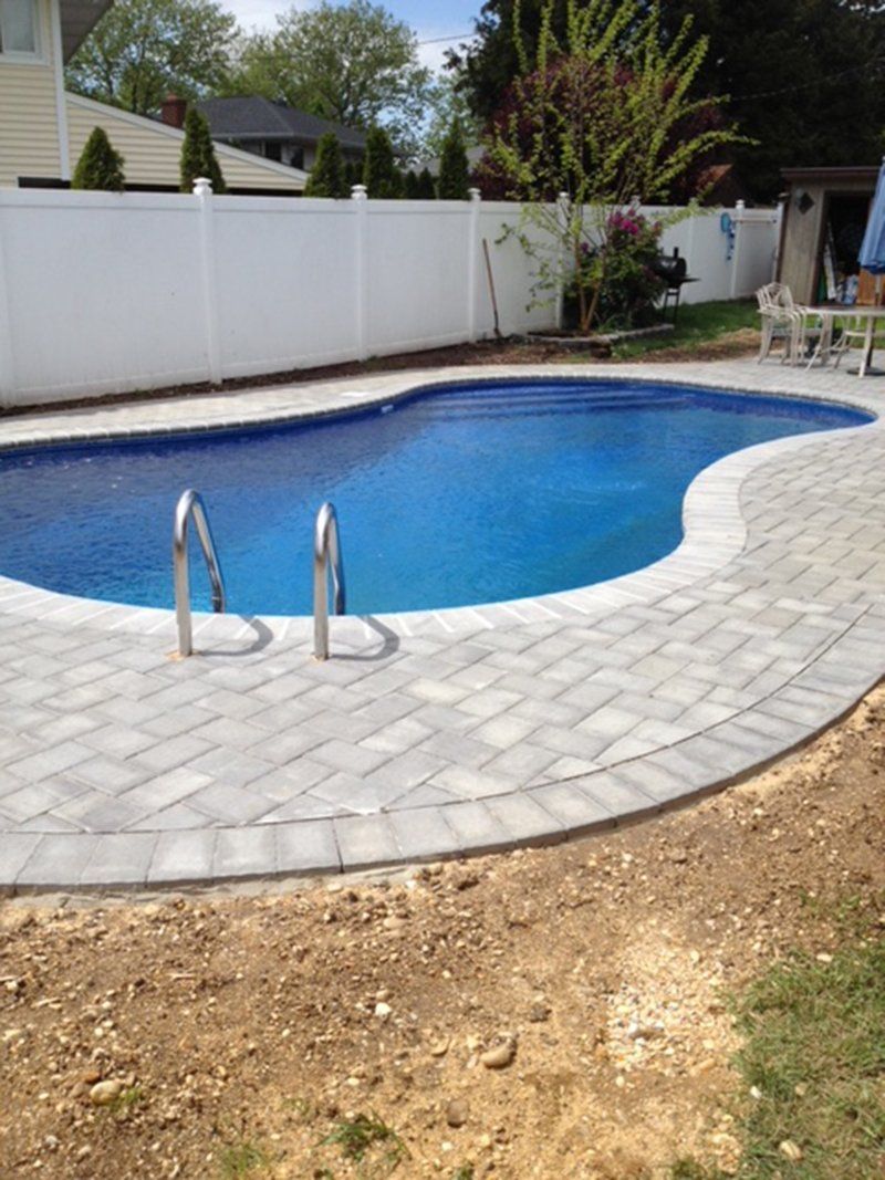 A in ground pool with grey bricks for patio