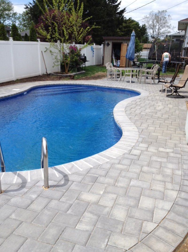A in ground pool with grey bricks for patio