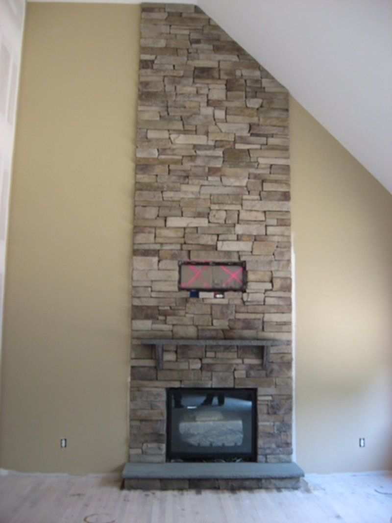 inside home fire place with multi colored stones above the fire place
