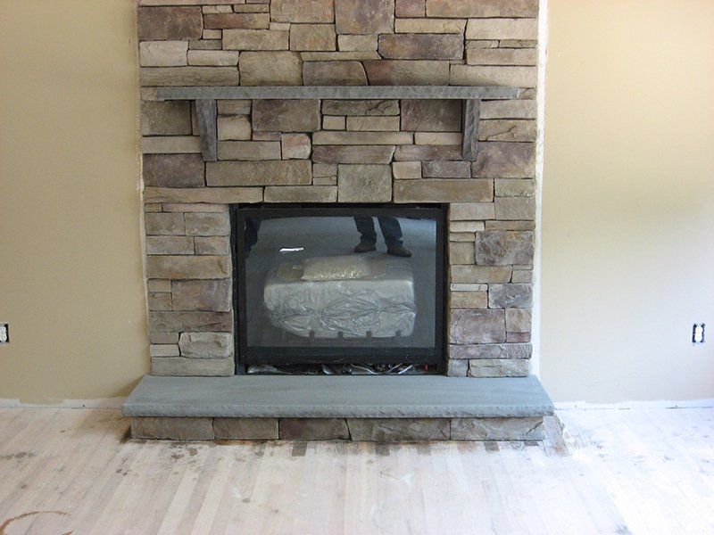 inside home fire place with multi colored stones above the fire place