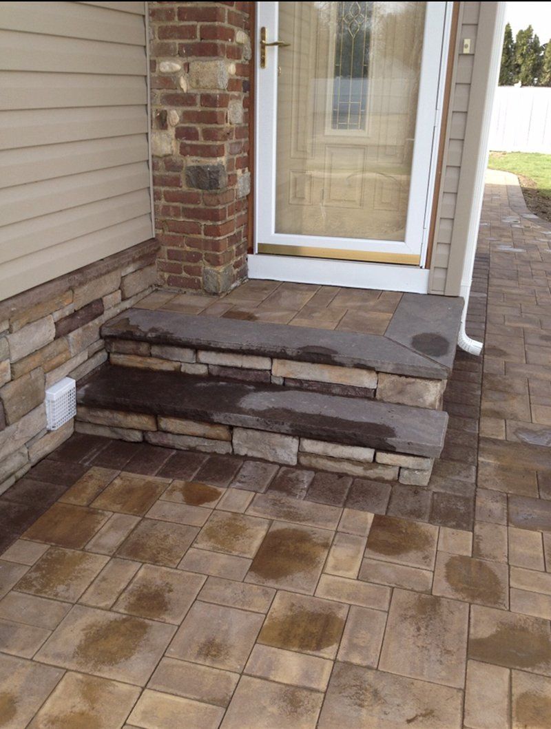 brown brick stoop with dark brown stone steps leading side entrance of a house