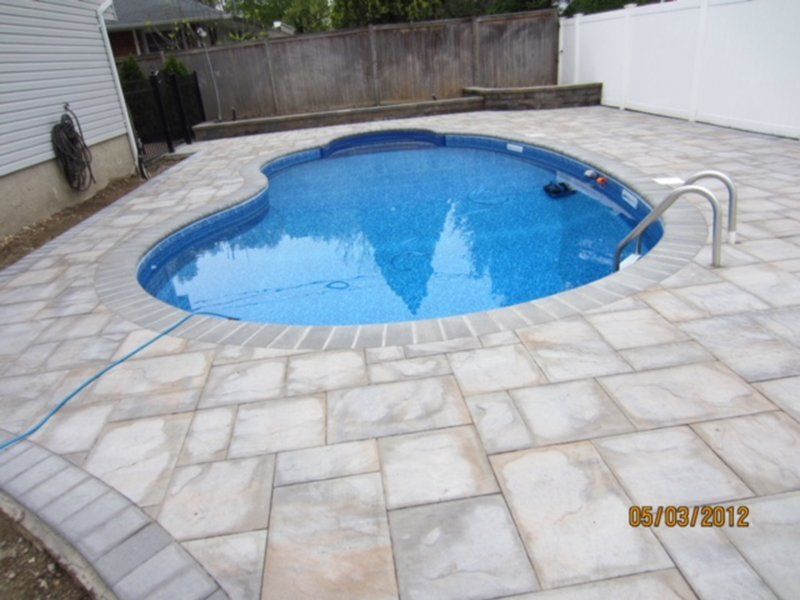 A in ground pool with grey bricks for patio