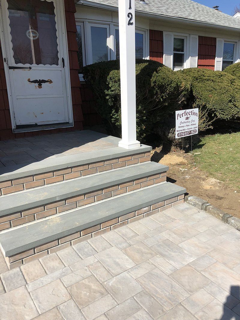 red brick stoop with grey stone steps leading to front door of a house