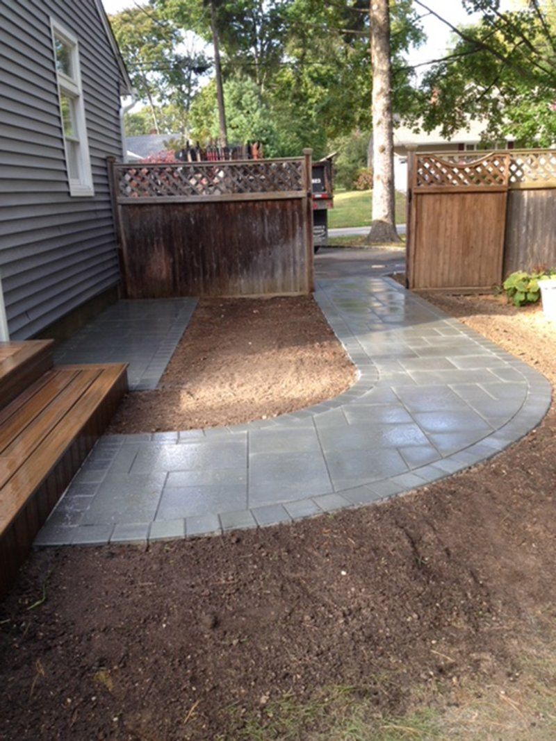 grey stone walkway with a open wooden fence leading to wooden steps