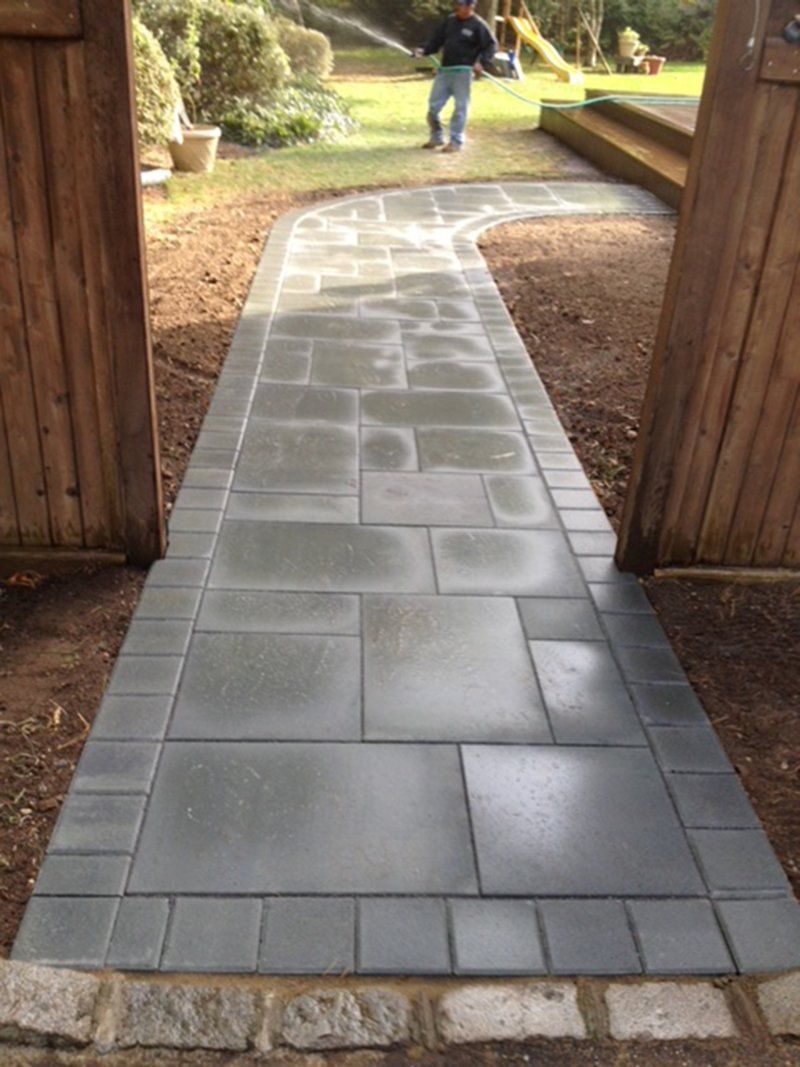 grey stone walkway with a open wooden fence