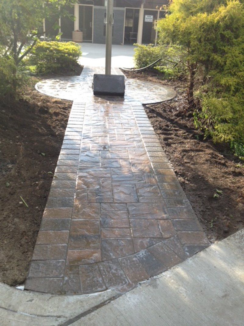 wet walkway made of stones that has a flag pole with a memorial stone at the base