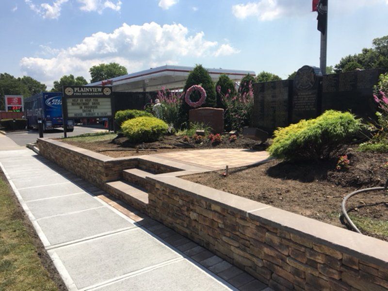 multi colored brick short wall with stone steps leading to memorial, next to a gas station
