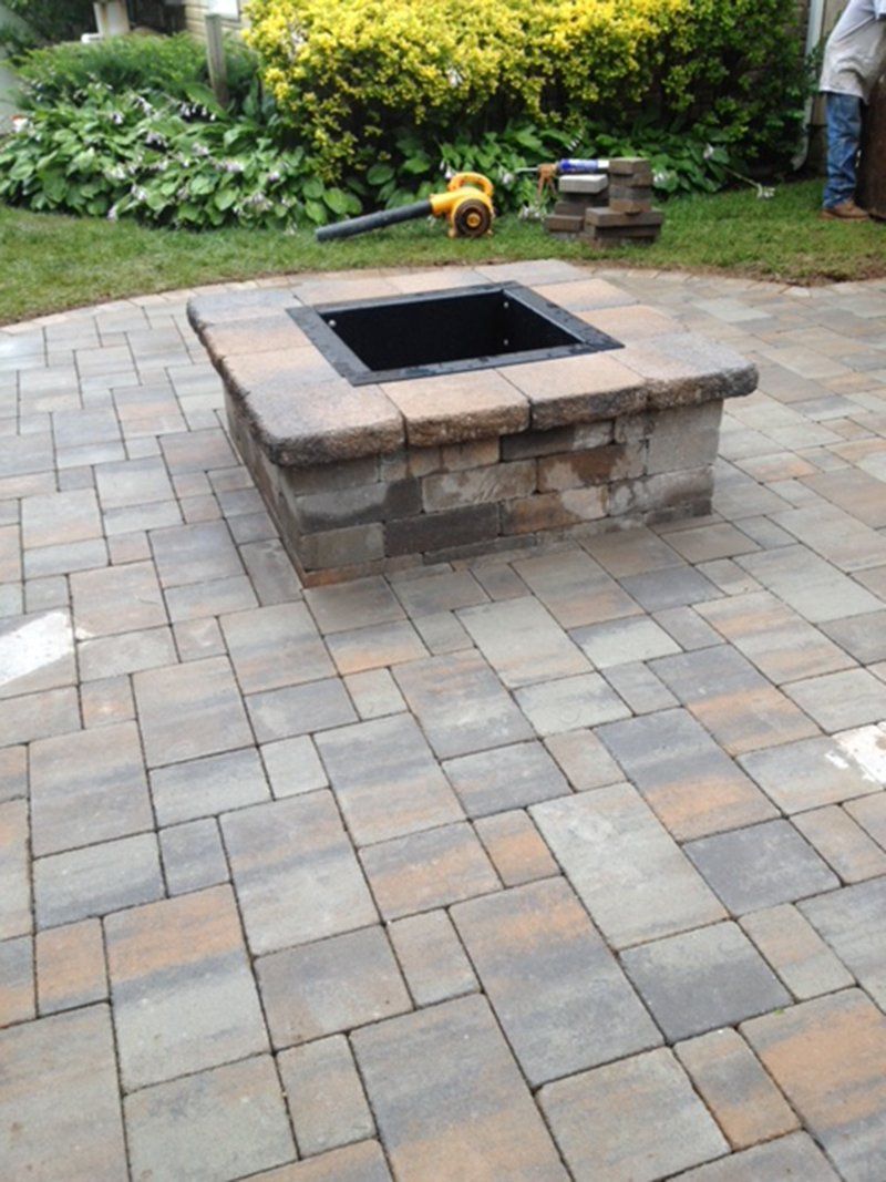 square bricked fireplace with a stone patio in the backyard