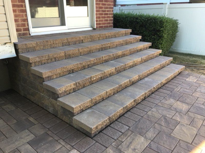 multi step stoop made of light brown stone leading to a stone patio