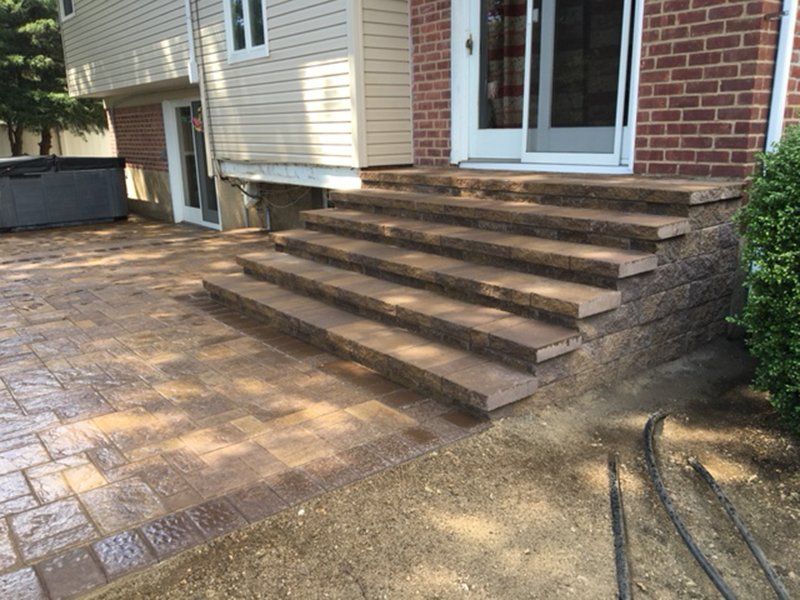 multi step stoop made of light brown stone leading to a stone patio