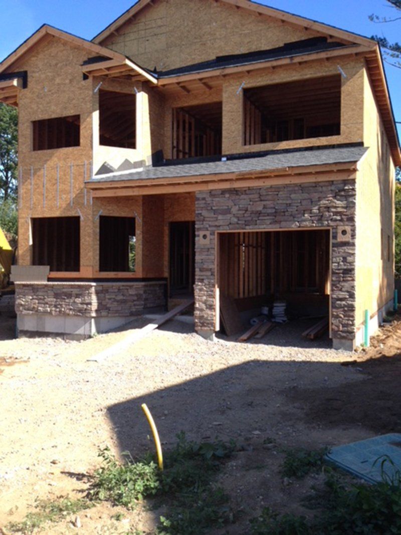 house being constructing with the start of stonework around the garage door