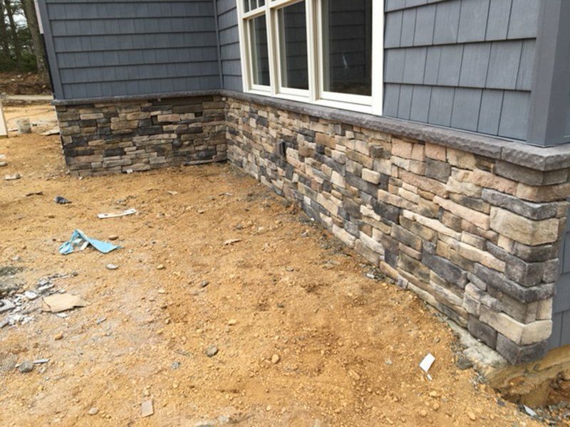 side of house with the bottom half covered in multi colored stones