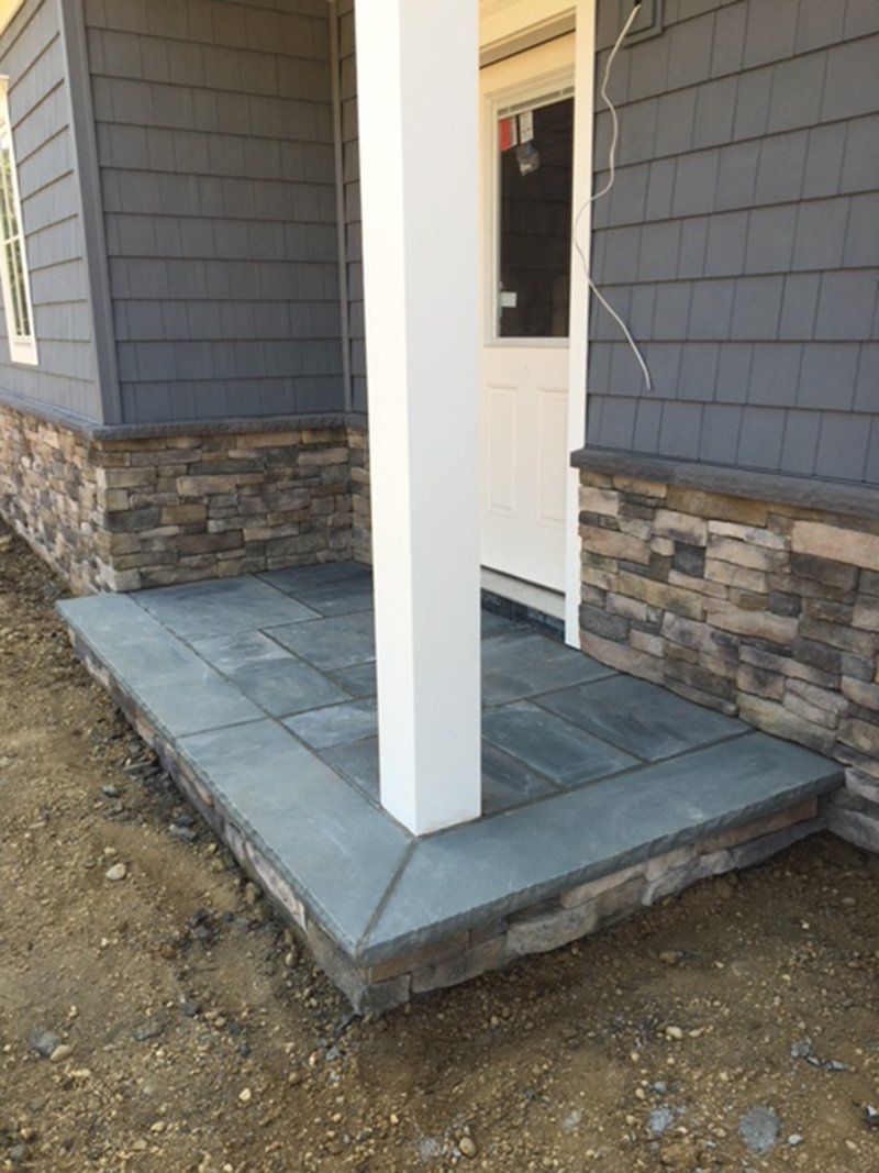 a dark grey stone stoop with a white support beam at the corner