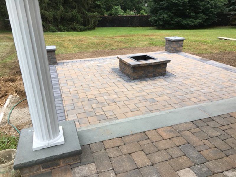 square bricked fireplace with a stone patio in the backyard