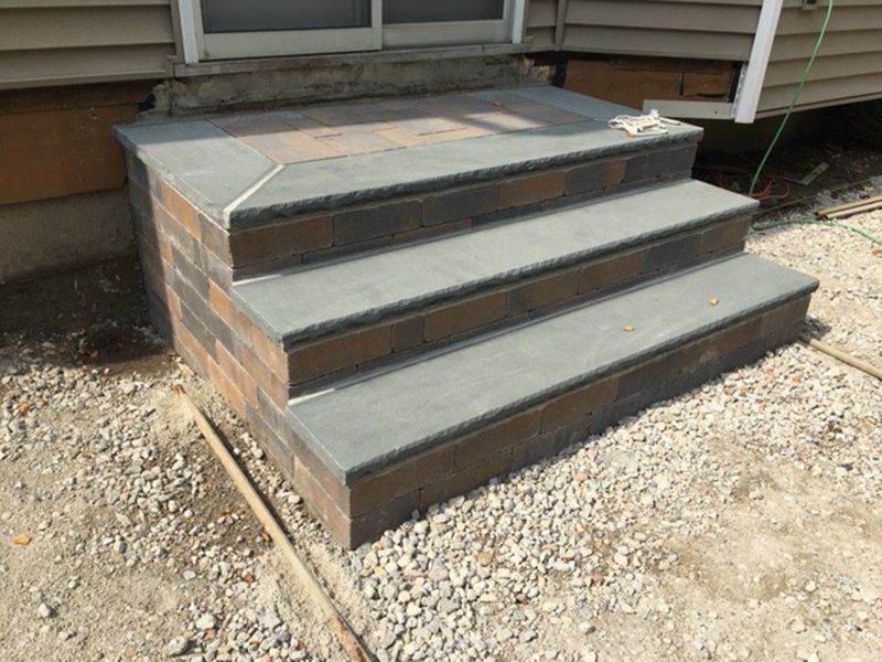 a 3 step grey stoop leading to a backyard