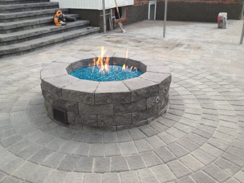 active round fire place filled with small blue stones in flame