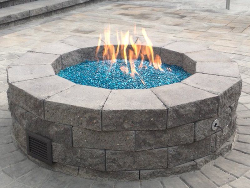 active round fire place filled with small blue stones in flame