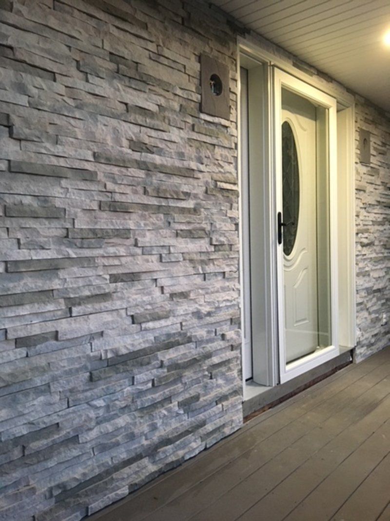 wall of house made of grey stone bricks around the front white door