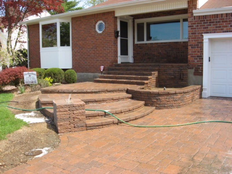 front of a house with brown brick stoop leading to driveway