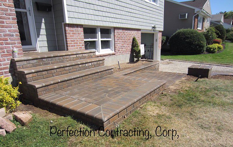 a four step grey brick stoop leading to the driveway