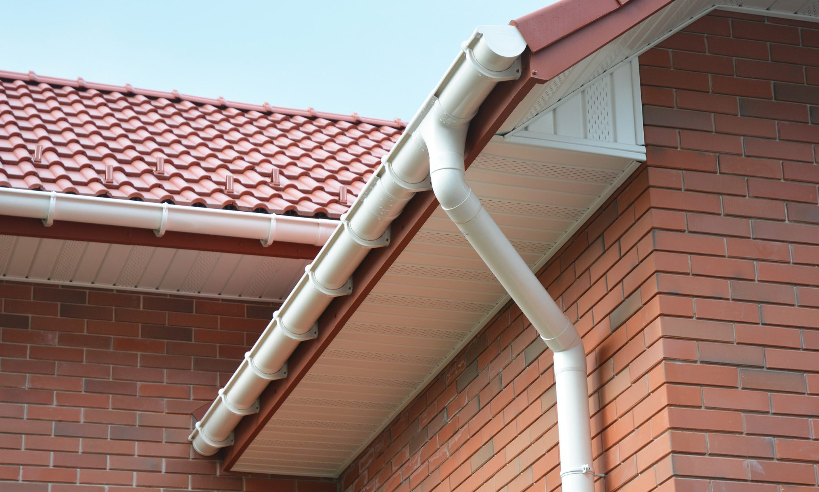 A red brick building with a white gutter on the side