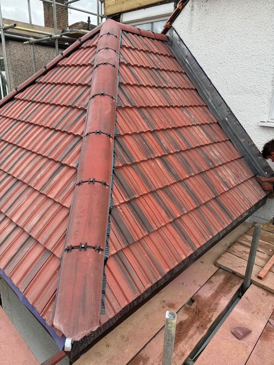 A red tiled roof is being installed on a house.