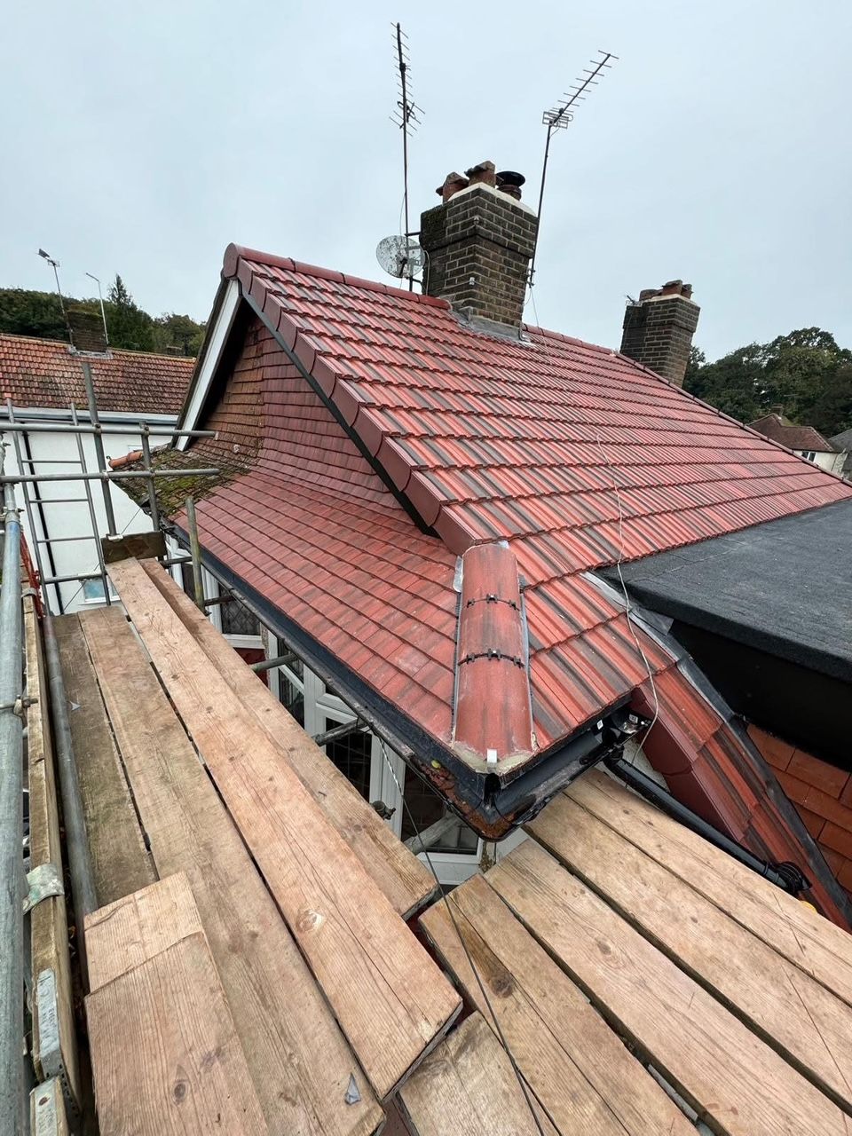 A red tiled roof is being built on top of a wooden scaffolding.