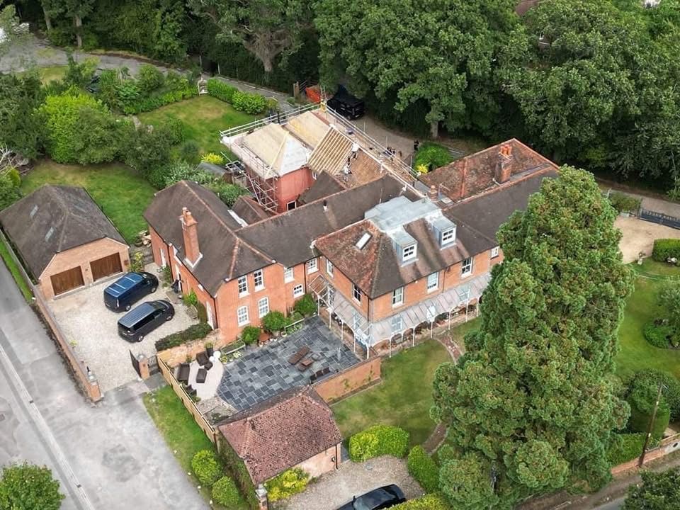 An aerial view of a large house with a lot of cars parked in front of it.