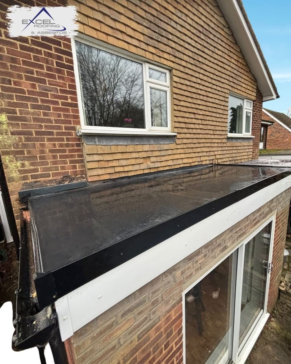 A brick house with a black roof and white windows.