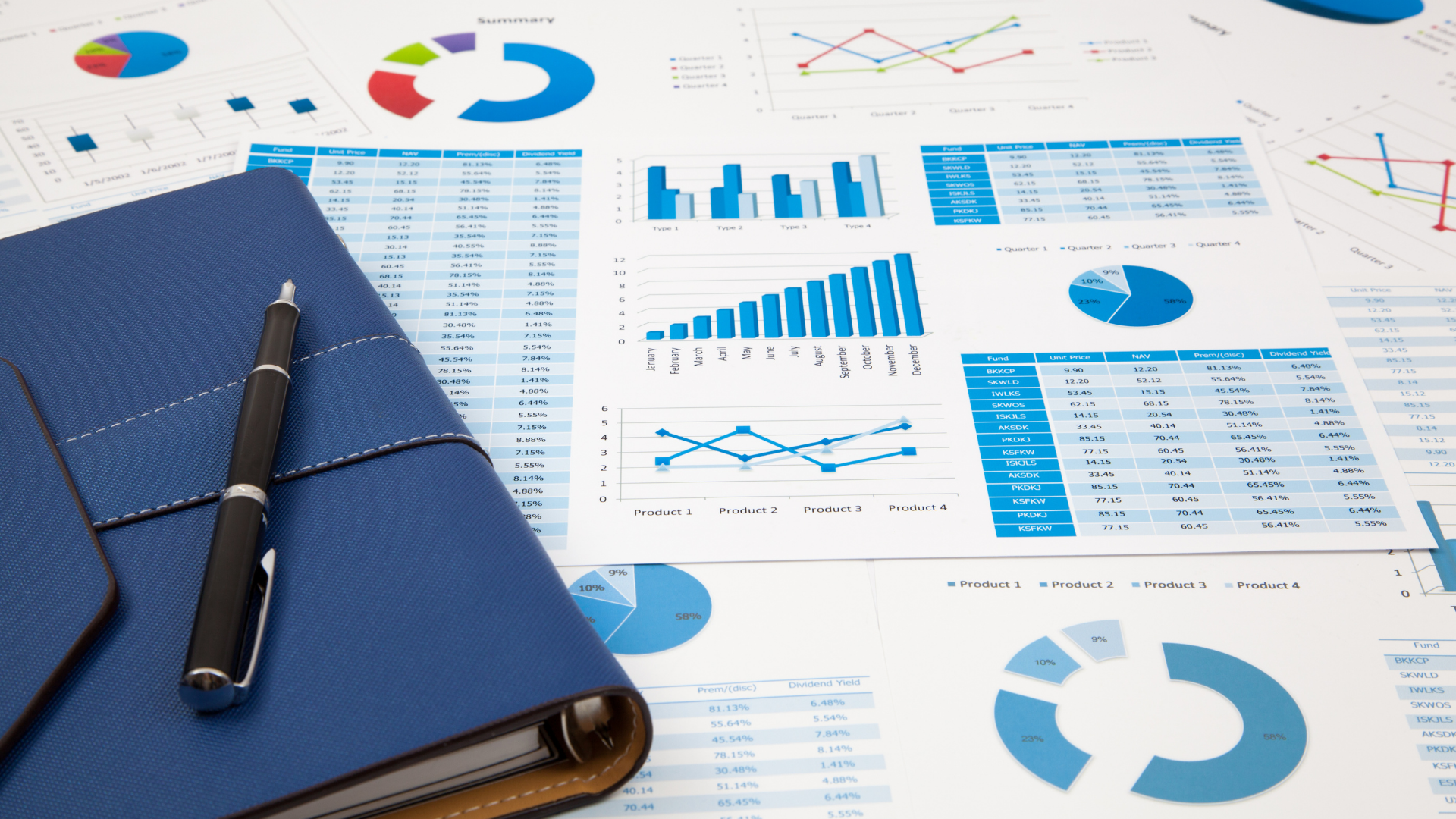 Blue notebook and pen on a desk covered with charts and financial data, with blue and white color scheme.