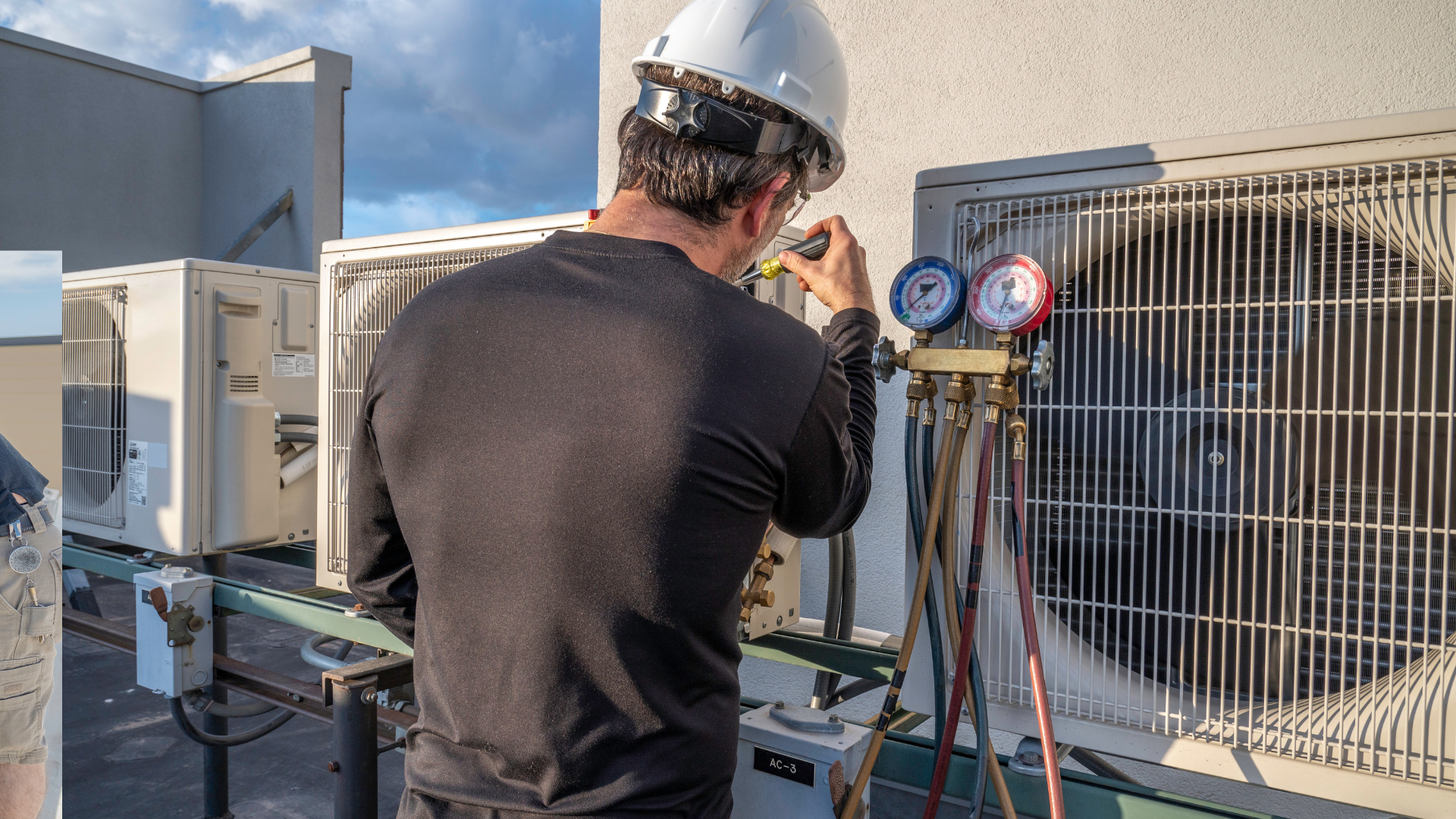 HVAC technician in hard hat checks AC units on a rooftop, using gauges.