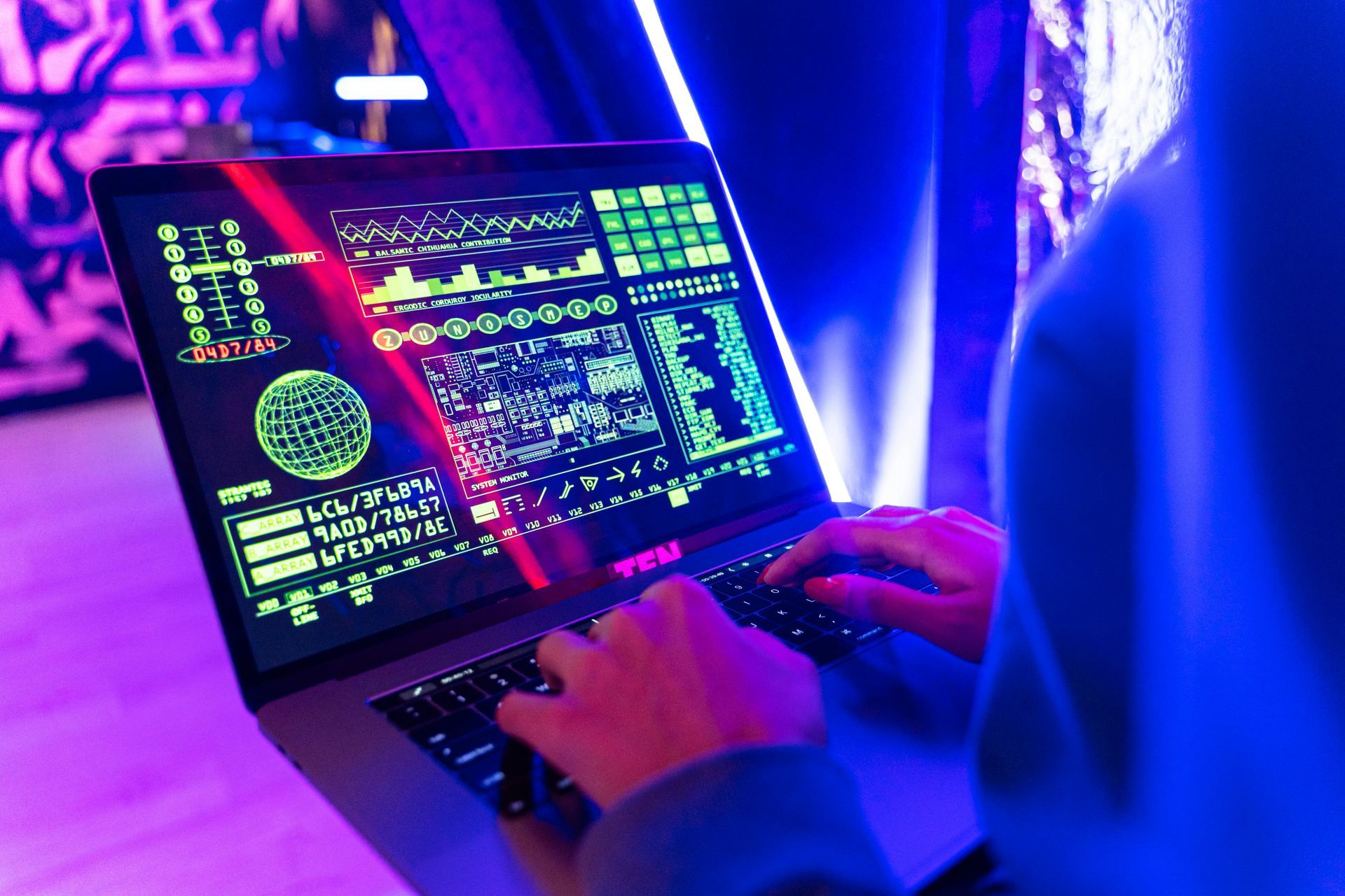 A person types on a laptop displaying complex data visualizations and code against a vibrant, neon-blue ambient background.